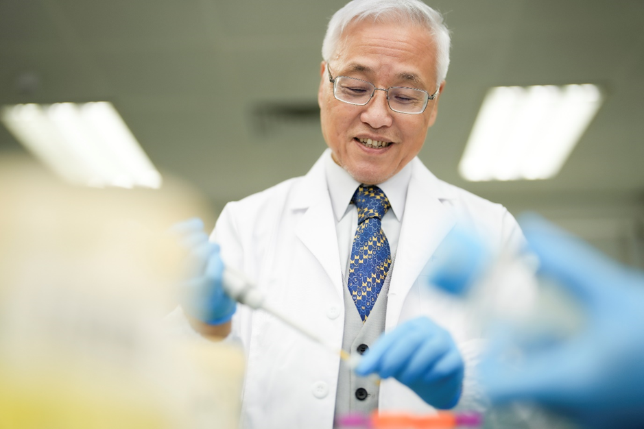 A person in a lab coat and blue gloves

Description automatically generated